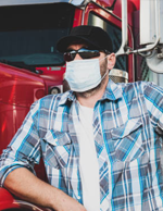 Photo of truck driver standing beside his truck wearing a mask