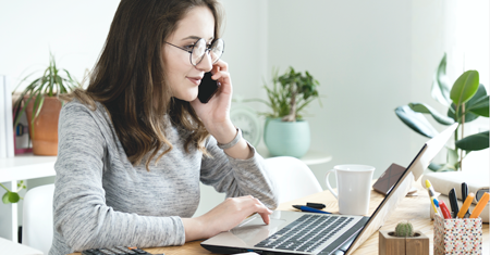 Photo of a person talking on a phone while looking at a computer, coordinating a schedule.