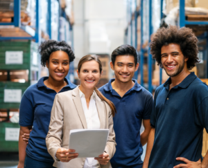 Warehouse manager and workers standing together with workplace in background.