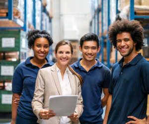 Warehouse manager and workers standing together with workplace in background.