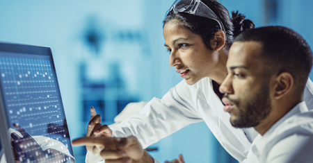 A photo of two medical professionals looking at research results on a computer.